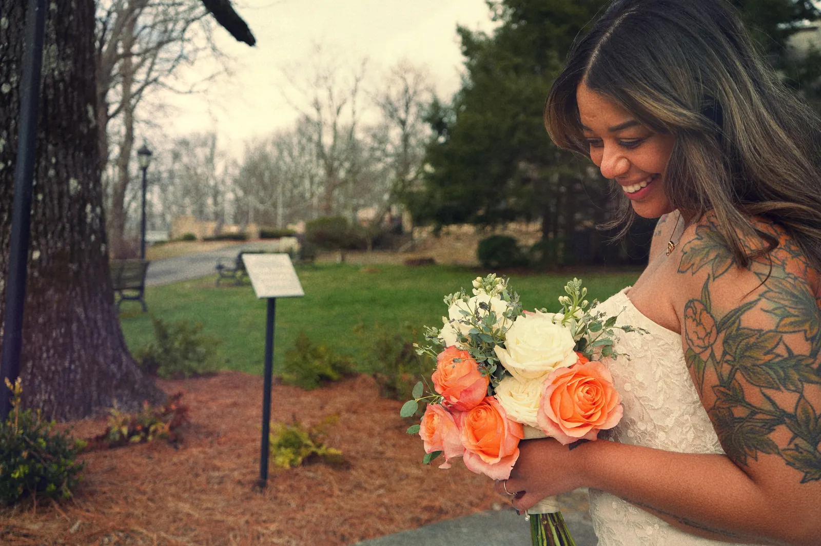 A bride holding a coral and cream rose bouquet from Wedding Box Florals